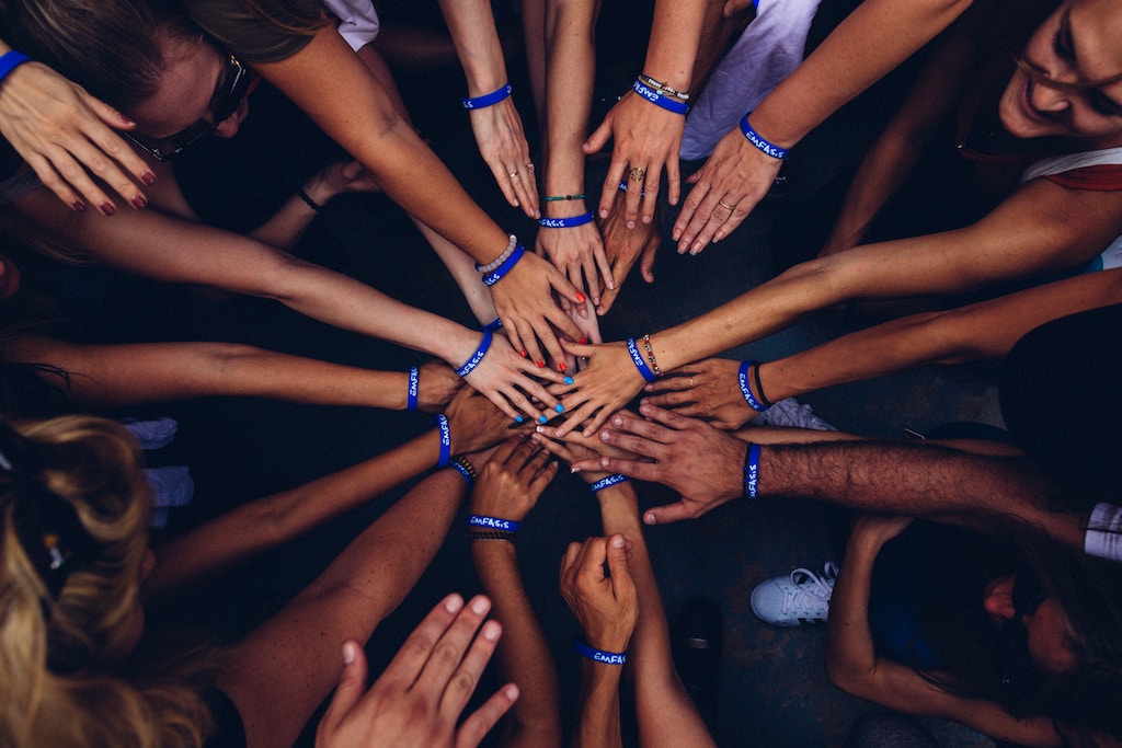 Gruppe legt die Hände mit blauen Armbändern zusammen